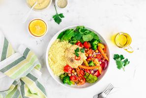 Baked vegetables with hummus bowl. Salad with baked potato, zucchini, broccoli and hummus.